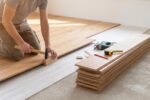 Poseur installant un parquet flottant dans une pièce lumineuse