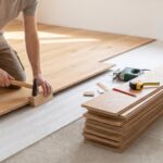 Poseur installant un parquet flottant dans une pièce lumineuse