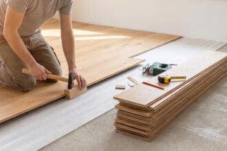 Poseur installant un parquet flottant dans une pièce lumineuse