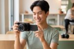 Jeune créateur de contenu débutant avec un Sony ZV-E10 ou un Canon R50 en main, choix d'appareil hybride.
