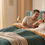 Couple souriant se réveillant sur un grand matelas confortable, lumière du matin douce