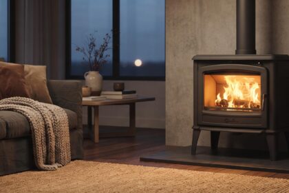 Poêle à bois Godin Châtel noir mat dans un salon cosy, flammes visibles à travers la vitre, ambiance chaleureuse