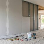Plaques de plâtre en cours de pose dans un salon moderne en rénovation, montrant les étapes du cloisonnement.