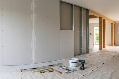 Plaques de plâtre en cours de pose dans un salon moderne en rénovation, montrant les étapes du cloisonnement.