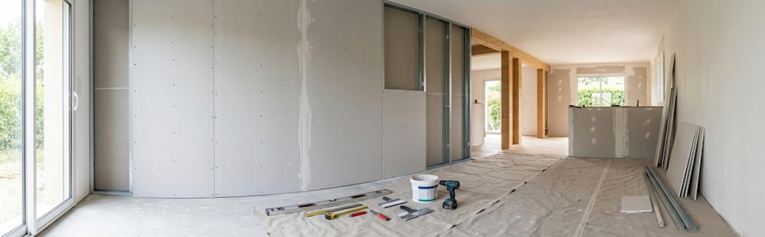 Plaques de plâtre en cours de pose dans un salon moderne en rénovation, montrant les étapes du cloisonnement.